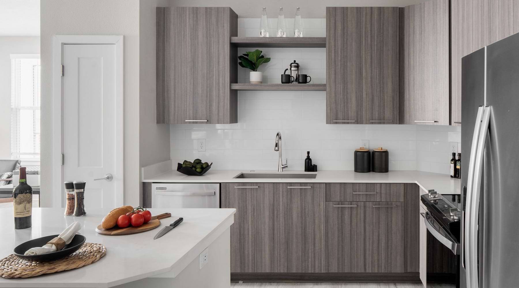 photograph of Aventon Soraya's apartment kitchens with brown slab cabinets, white quartz countertops and white subway tile backsplash photograph of Aventon Soraya's apartment kitchens with brown slab cabinets, white quartz countertops and white subway tile backsplash